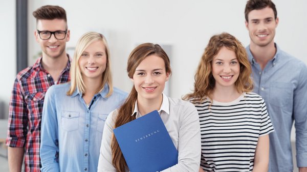 Fünf junge Männer und Frauen mit einer Bewerbungsmappe.